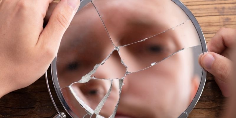 Refleksija u ogledalu koja simbolizuje suočavanje sa sopstvenim ponosom i ulogom žrtve.